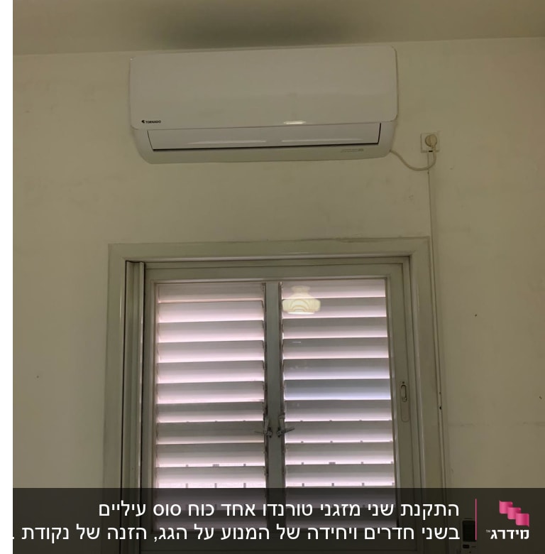 מזגן מותקן על קיר מעל חלון עם שלט רחוק